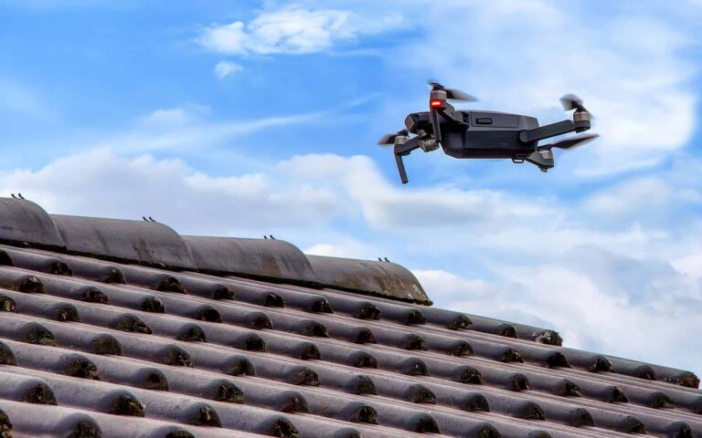 Side-view-of-a-black-drone-flying-over-roof