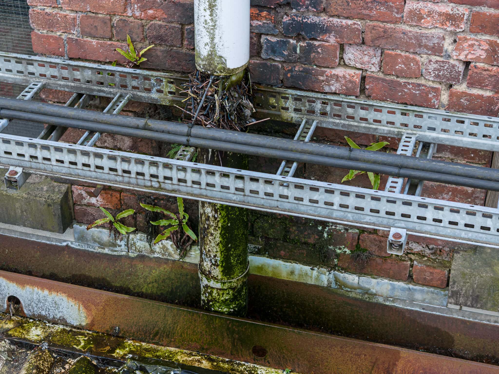 Survey drone hovering above red brick industrial building with flat roof during commercial property inspection