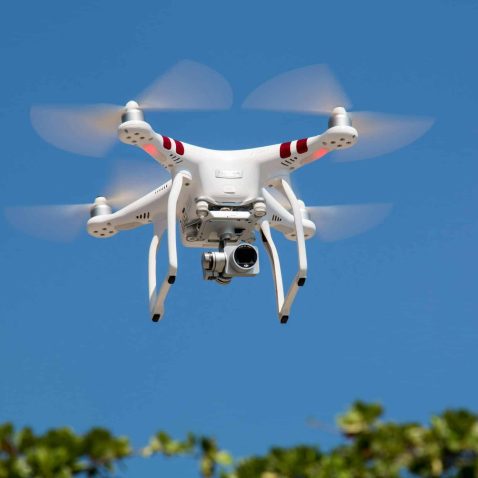 A white drone flying with camera against a clear blue sky in La Libertad drones UAVs and UAS.