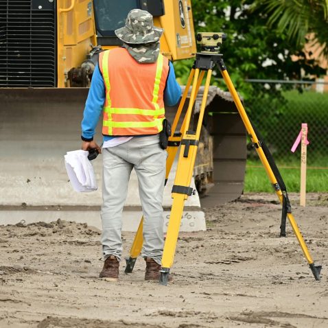 Drone videography & Time Lapse 7 A surveyor with equipment conducts measurements on a construction site.